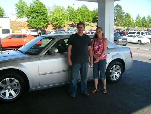 Customer standing next to their new car in a dealership
