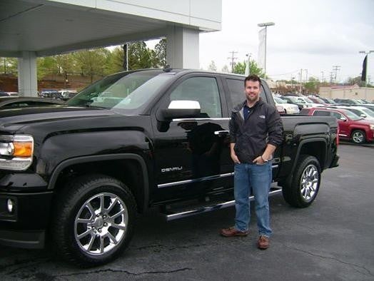 Customer standing next to their new car in a dealership